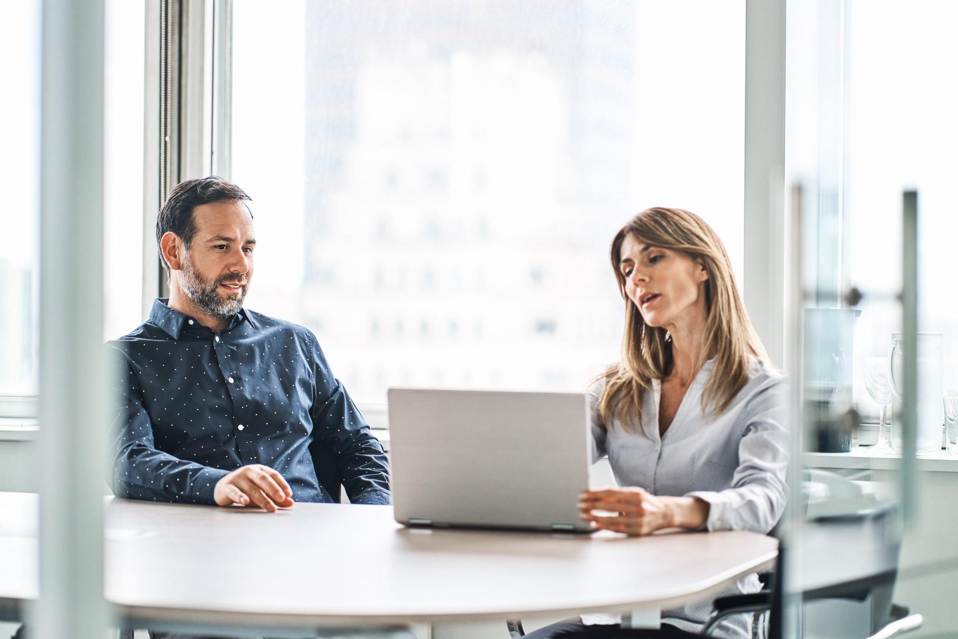 Colleagues discussing over laptop in office