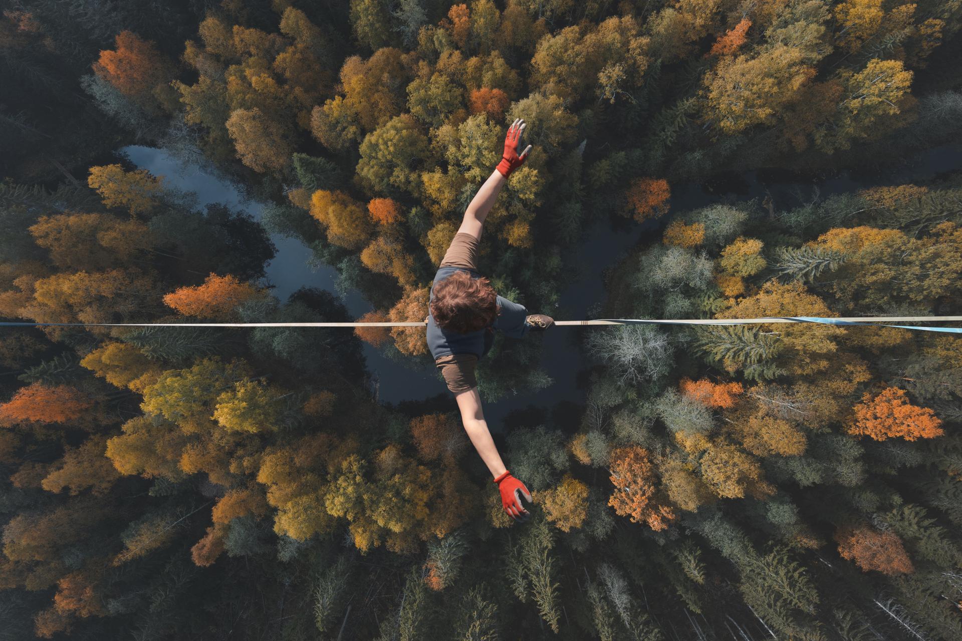 Highline over the forest. Rope walker walks on a rope at high altitude. Drone view. Slackline theme